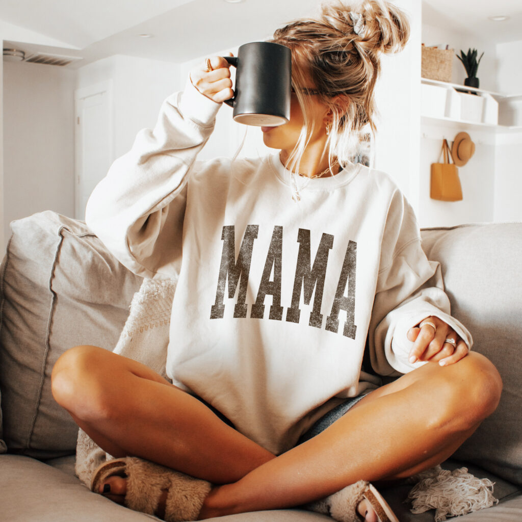 a woman wearing a trendy mama crewneck sweatshirt in Sand