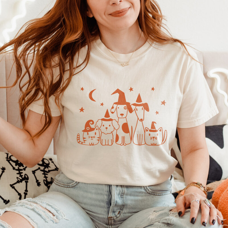 a woman wearing a witch pets comfort colors tee in ivory