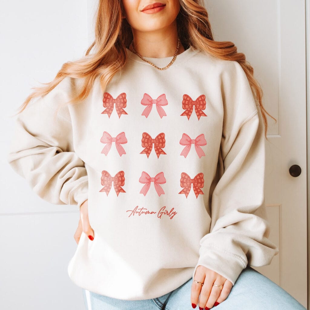 a woman wearing an Autumn Girly Coquette Sweatshirt in sand