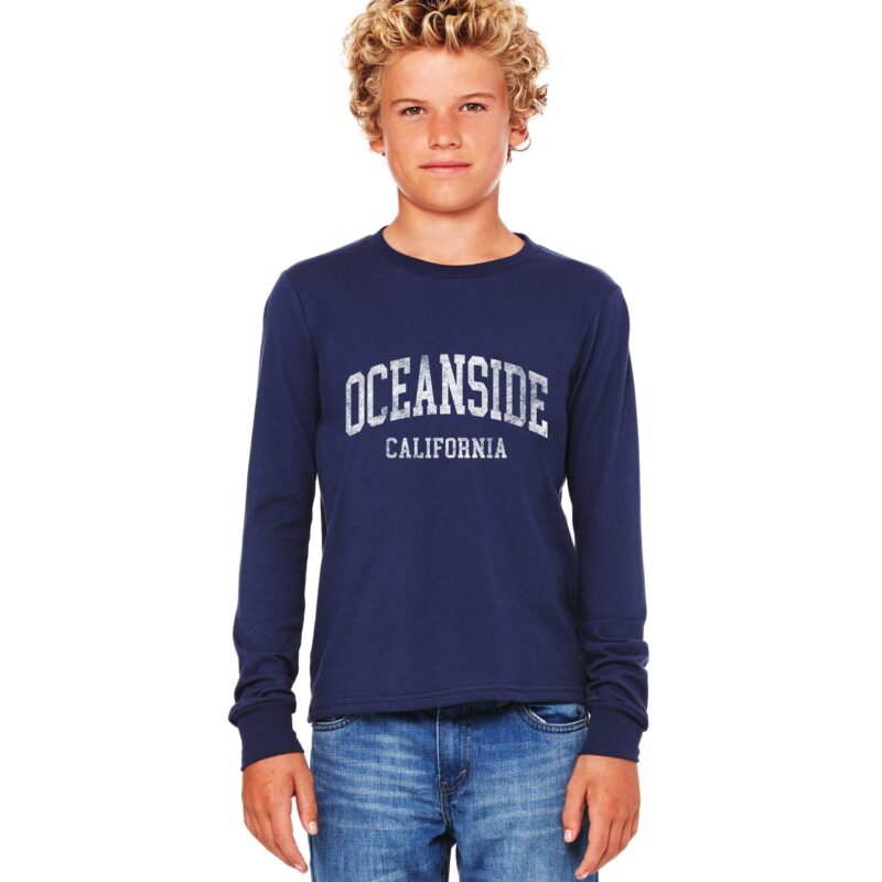 a custom youth long sleeve tee shown on a young boy wearing a long sleeve oceanside youth tee in navy