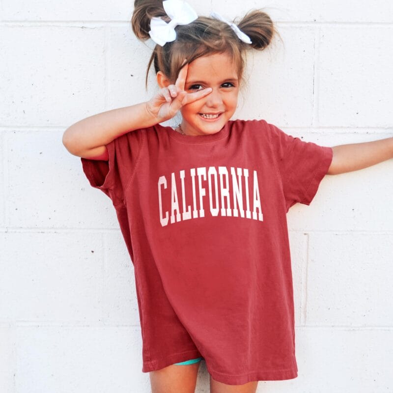 a little girl wearing a California Garment Dyed Kids Tee in crimson