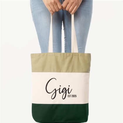 a woman holding a personalized grandma bag in forest, that says Gigi, Est. 2025