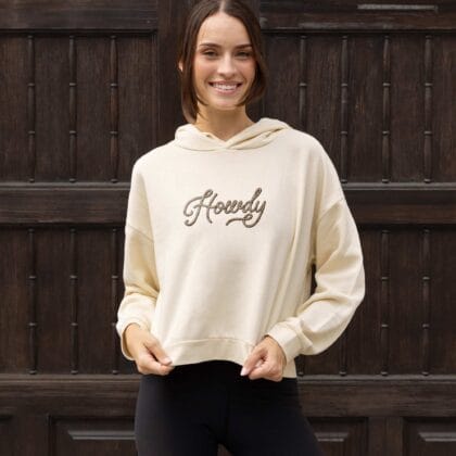 a woman wearing a howdy womens hip hoodie in bone