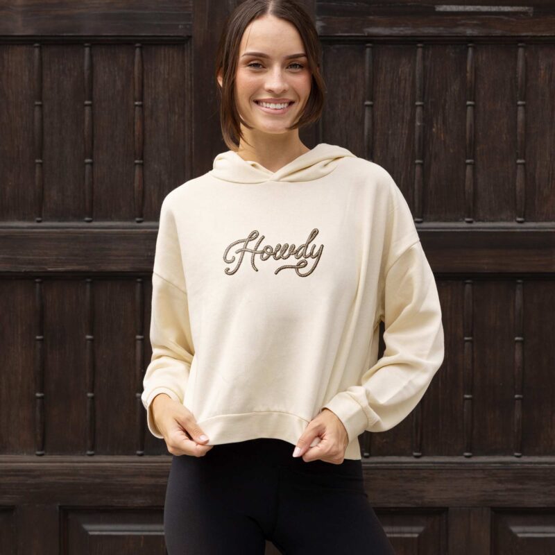a woman wearing a howdy womens hip hoodie in bone