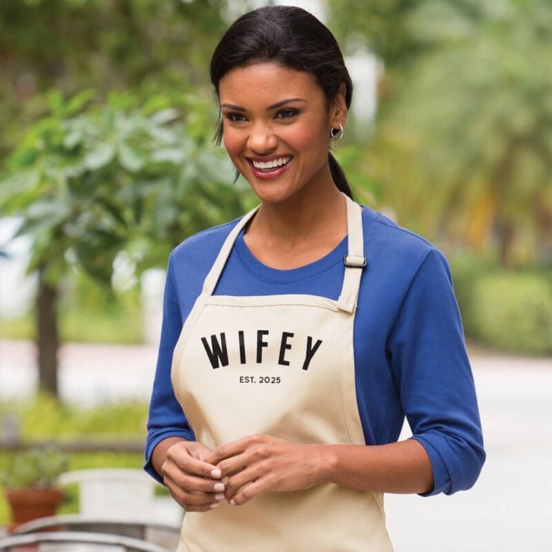 a woman wearing a personalized wifey apron in natural