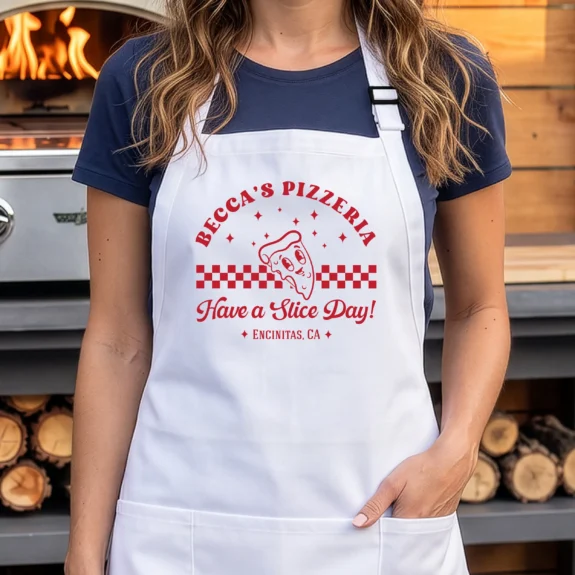 White personalized pizza apron beside an outdoor pizza oven