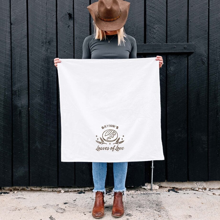 a woman holding a personalized sourdough loaves tea towel in white