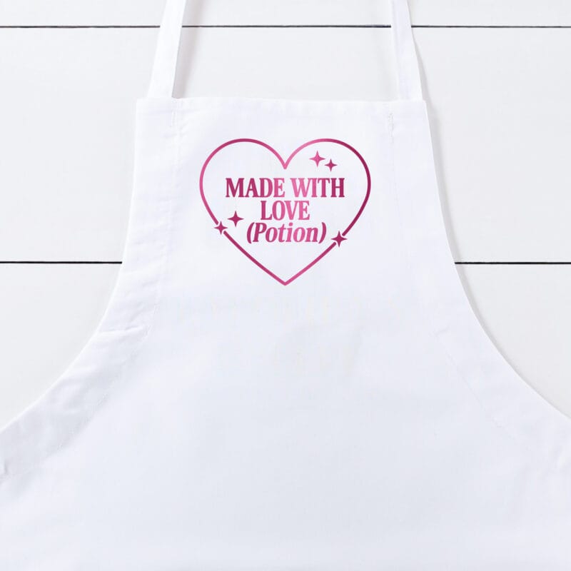 a Made With Love Potion Butcher Apron in white with a cherry metallic print