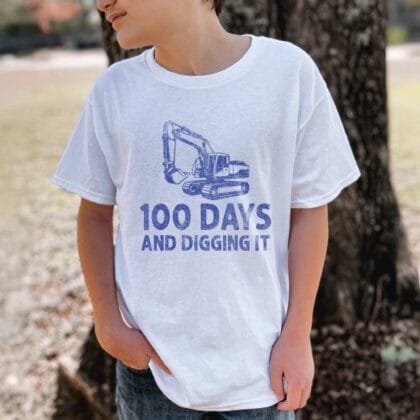 a young boy wearing an Excavator Shirt 100 Days in white