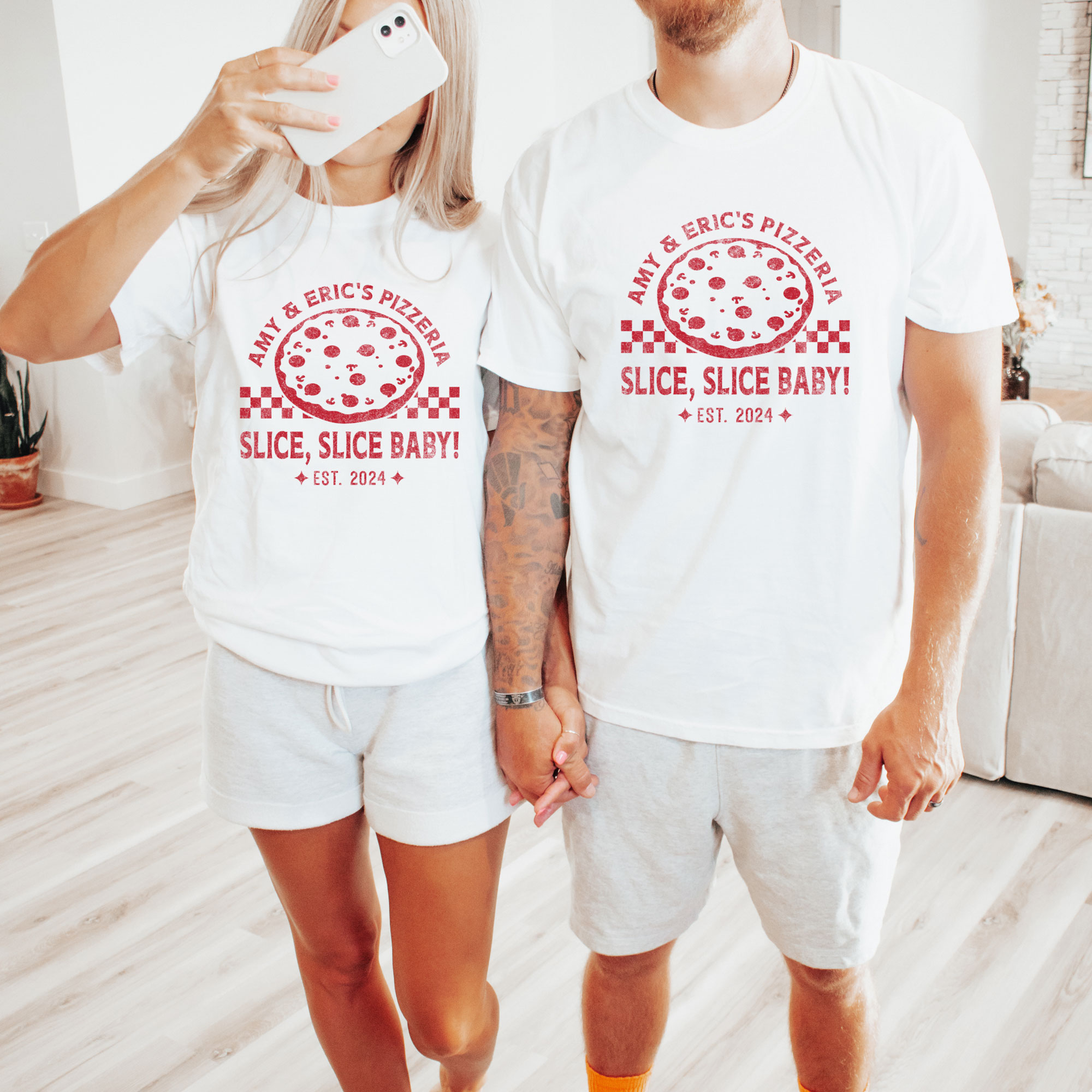a man and woman holding hands, wearing matching checkered pizza t-shirts in white