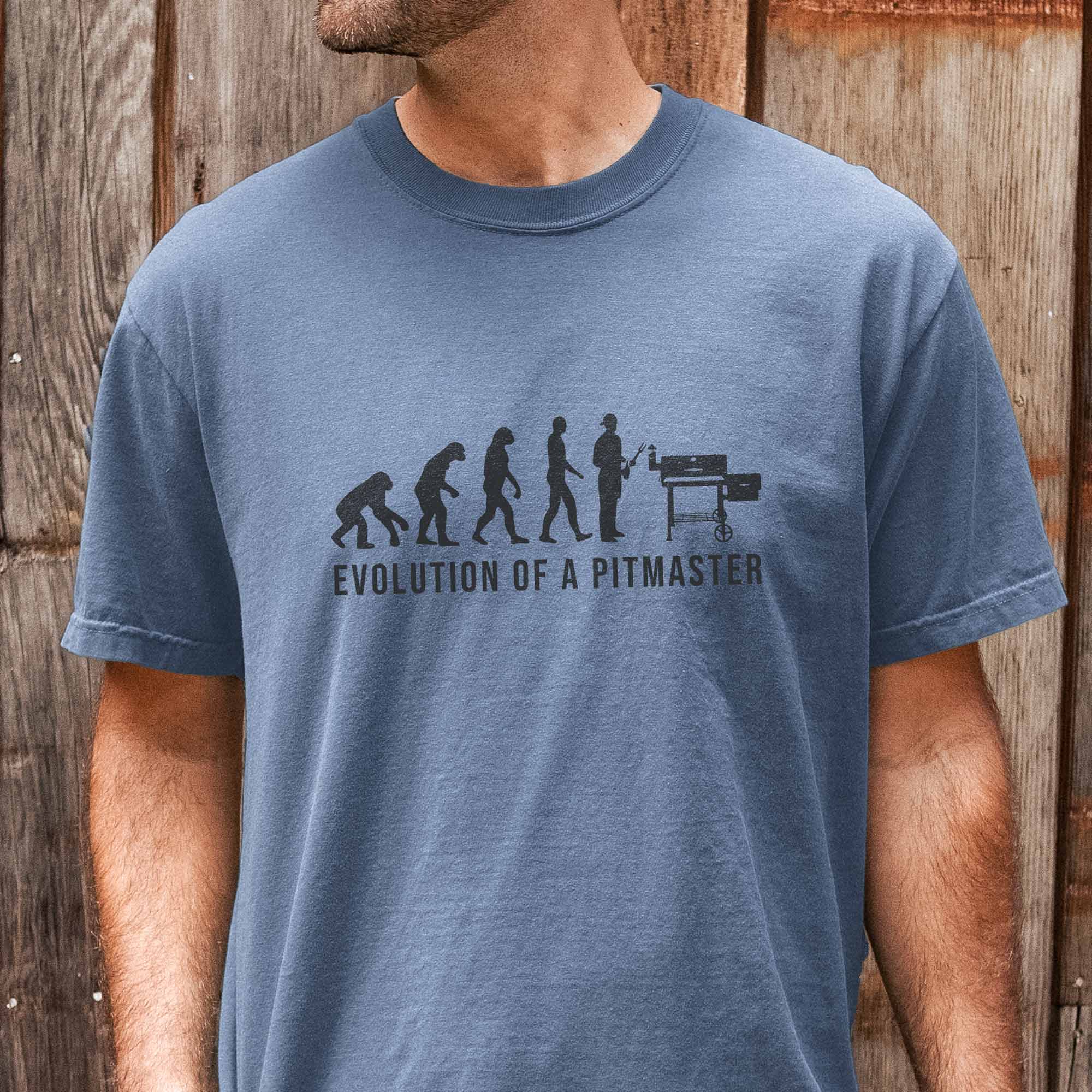 a man wearing an Evolution Of A Pitmaster Shirt in blue jean