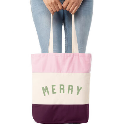 a woman holding a merry Christmas tote bag in burgundy