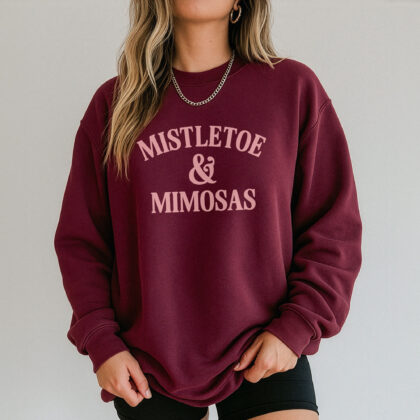 a woman wearing a Mistletoe And Mimosas Sweatshirt in maroon