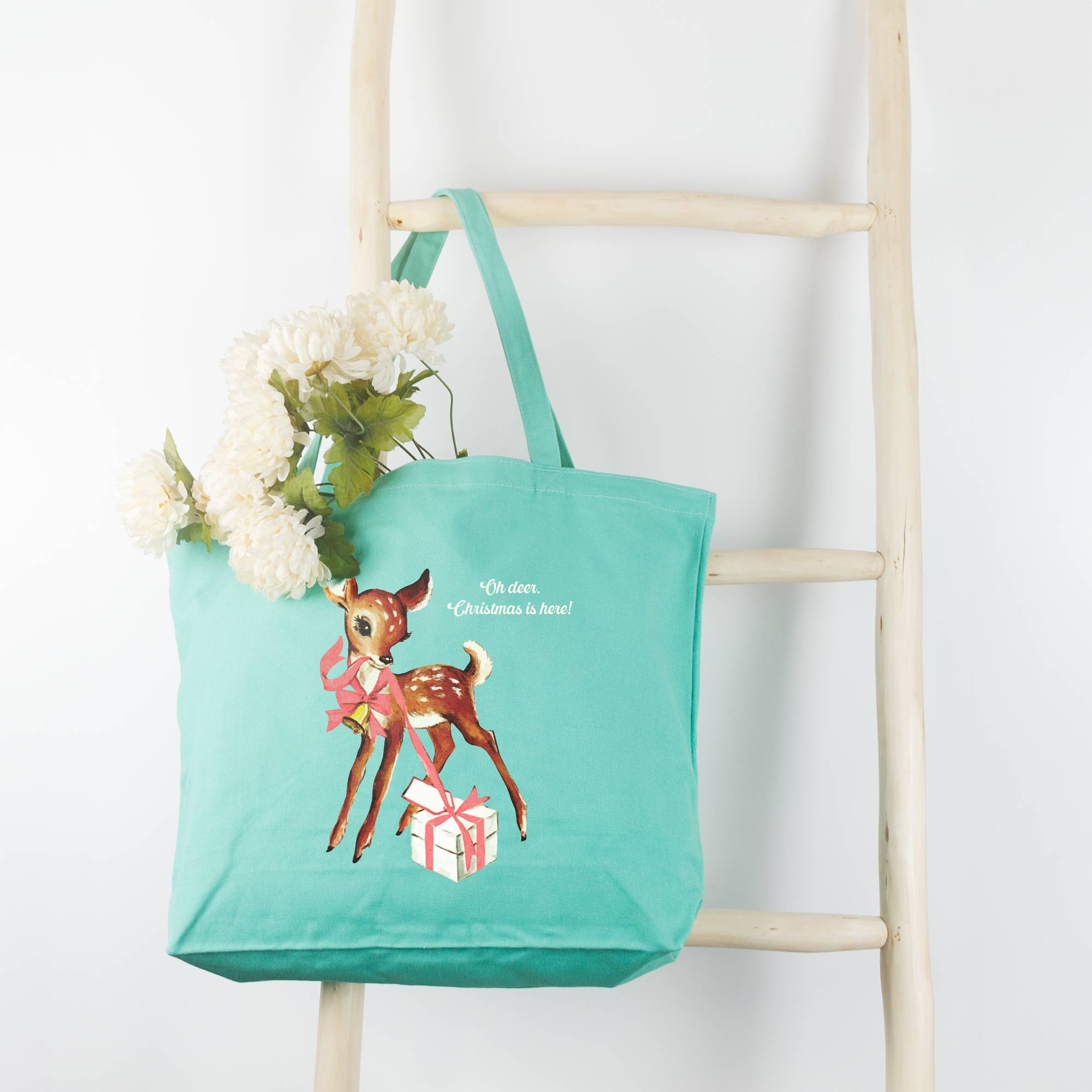 a Retro Deer Tote in sea glass, hanging on a wooden ladder