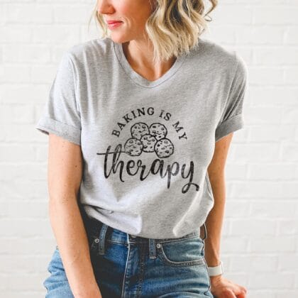 a woman wearing a Baking Is My Therapy Shirt, with a cookie graphic, in athletic heather