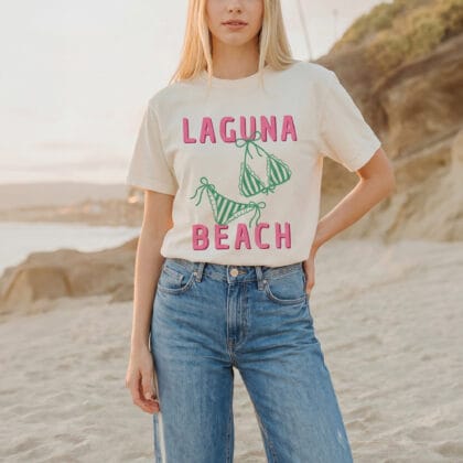 a young woman on the shore, wearing a pink and green Laguna Beach Shirt in ivory