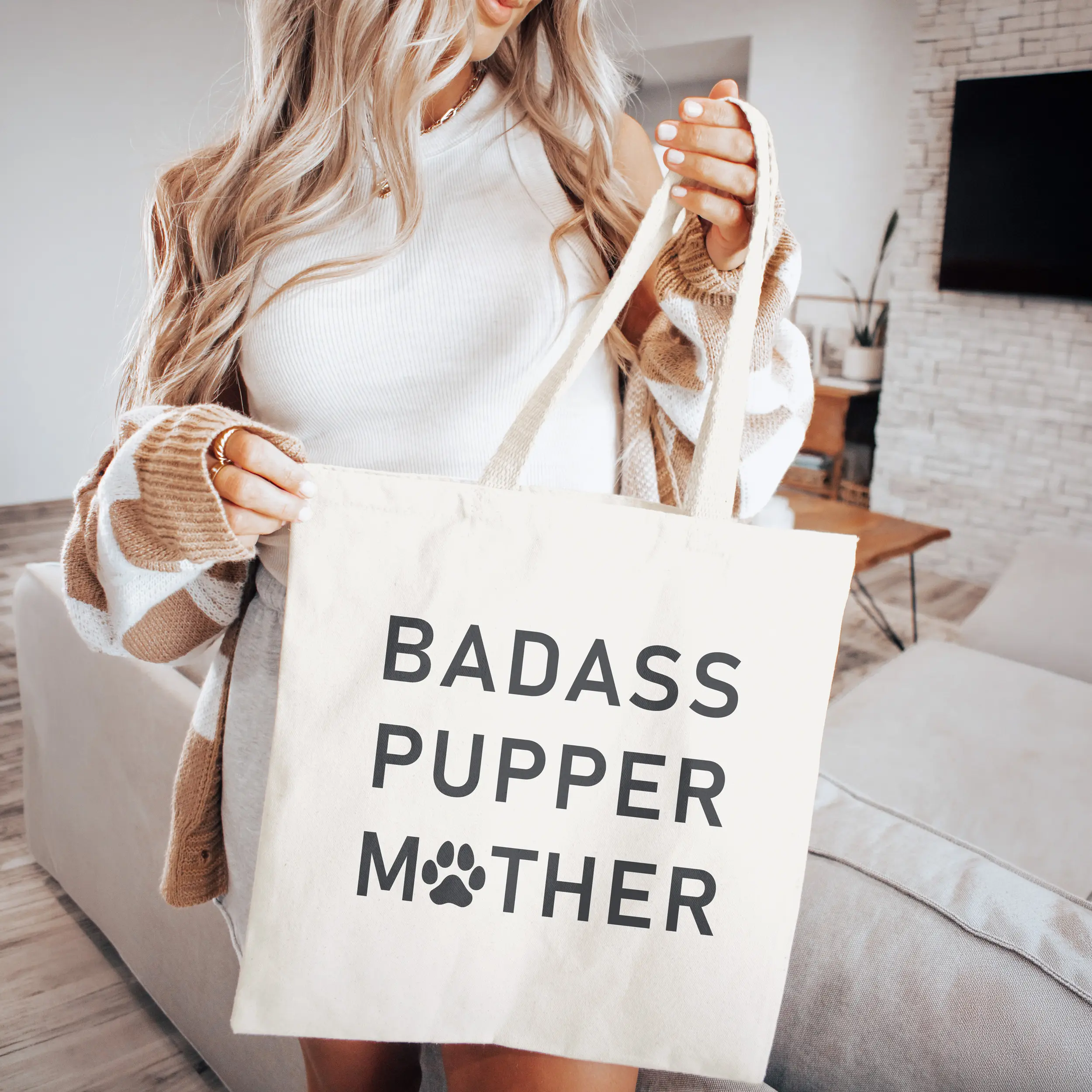 a woman holding a a badass pupper mother tote bag in natural