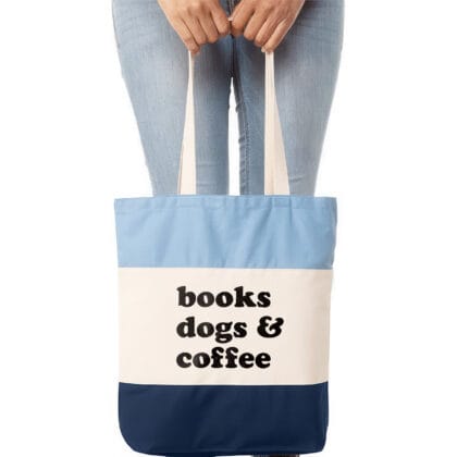 a woman holding a books dogs and coffee tote in blue