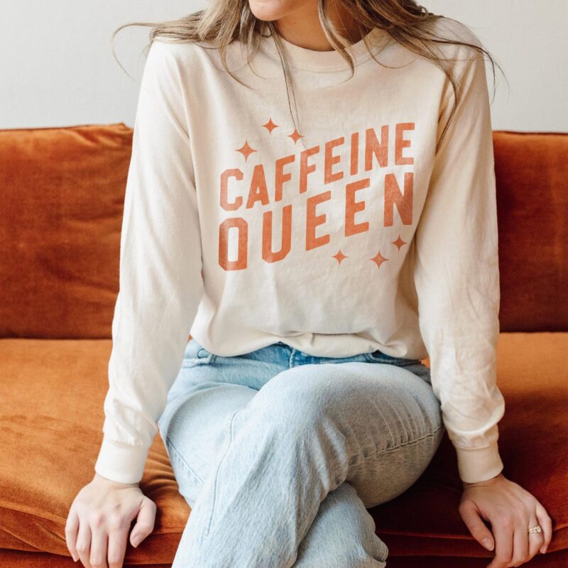 a young woman wearing a long sleeved, caffeine queen tee in Ivory