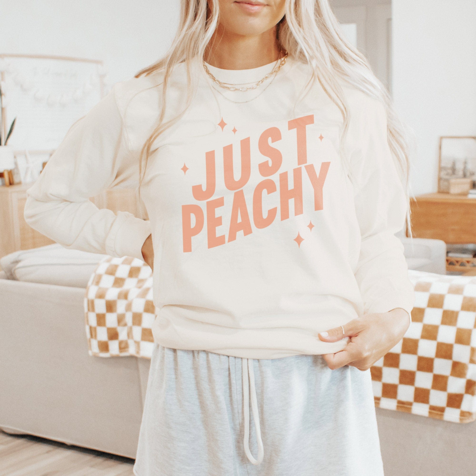 A young woman wearing a Just Peachy Long Sleeve Tee in ivory