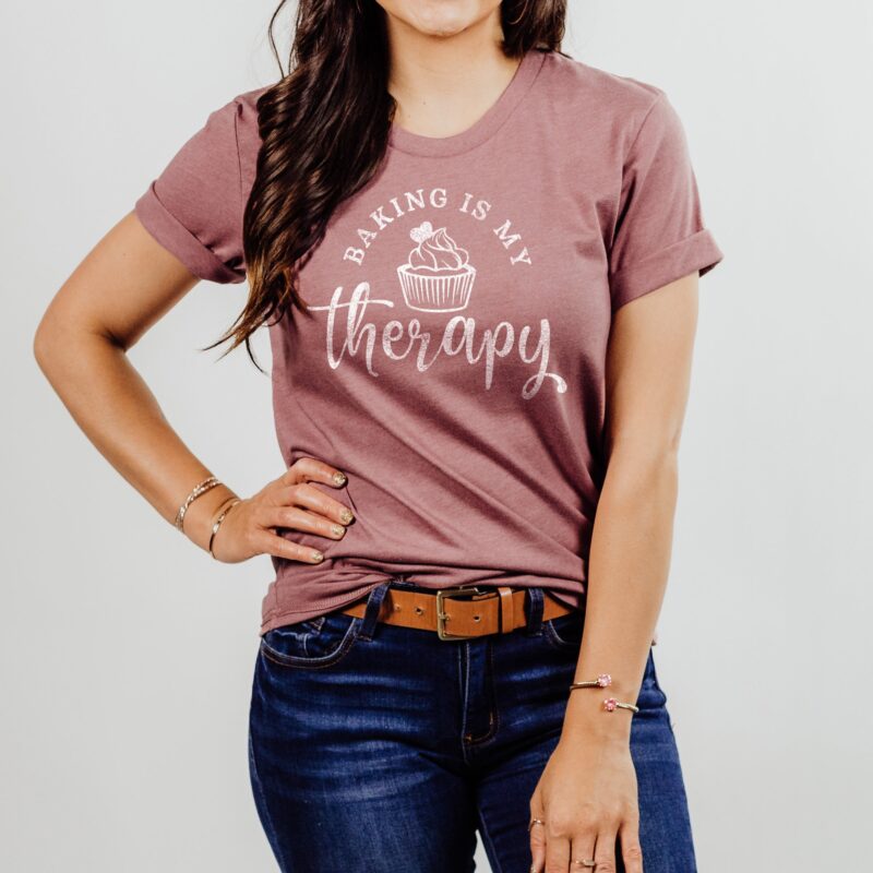 A young woman wearing Baking Is My Therapy Cupcake Shirt in mauve