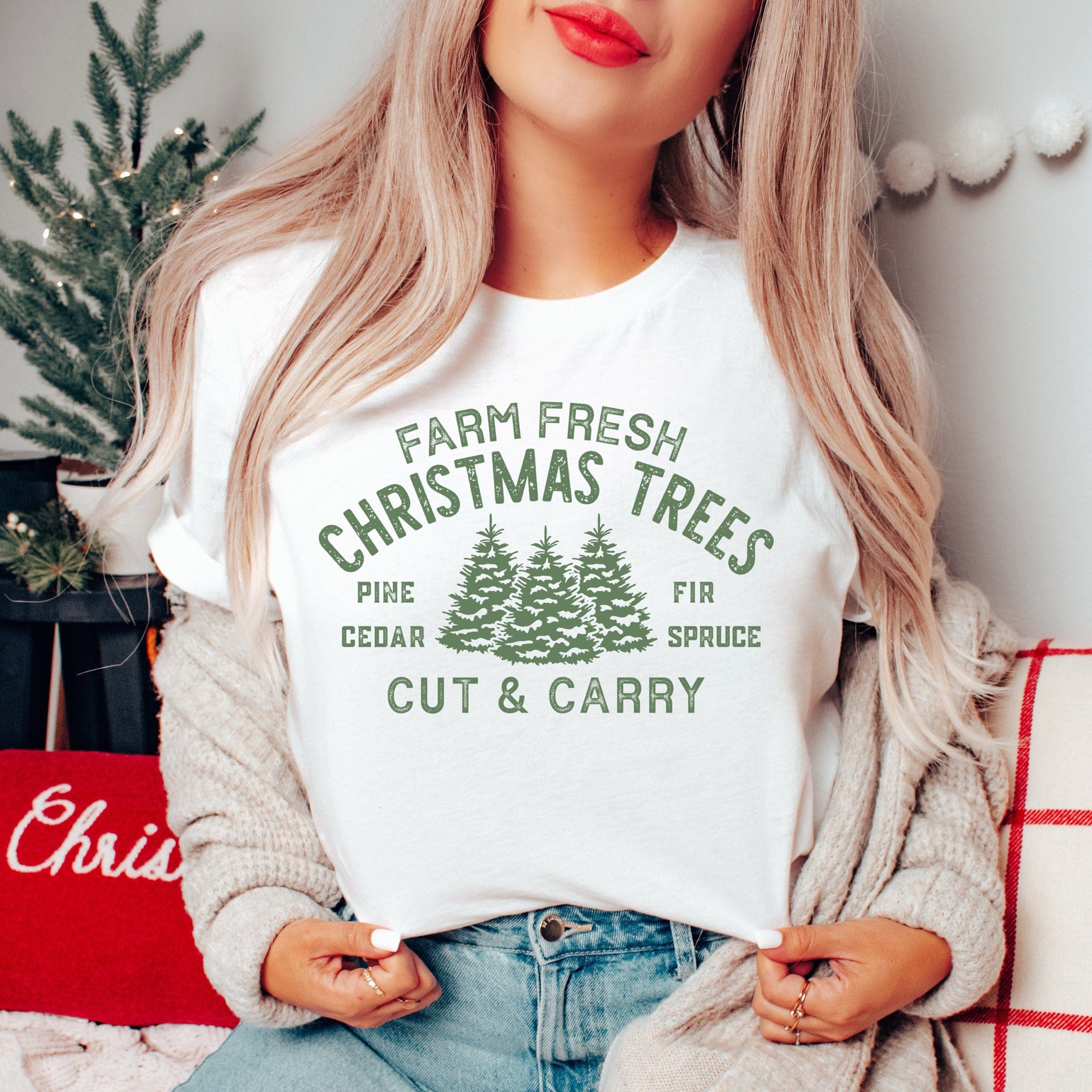 a young woman in a christmas scene wearing a farm fresh Christmas trees shirt