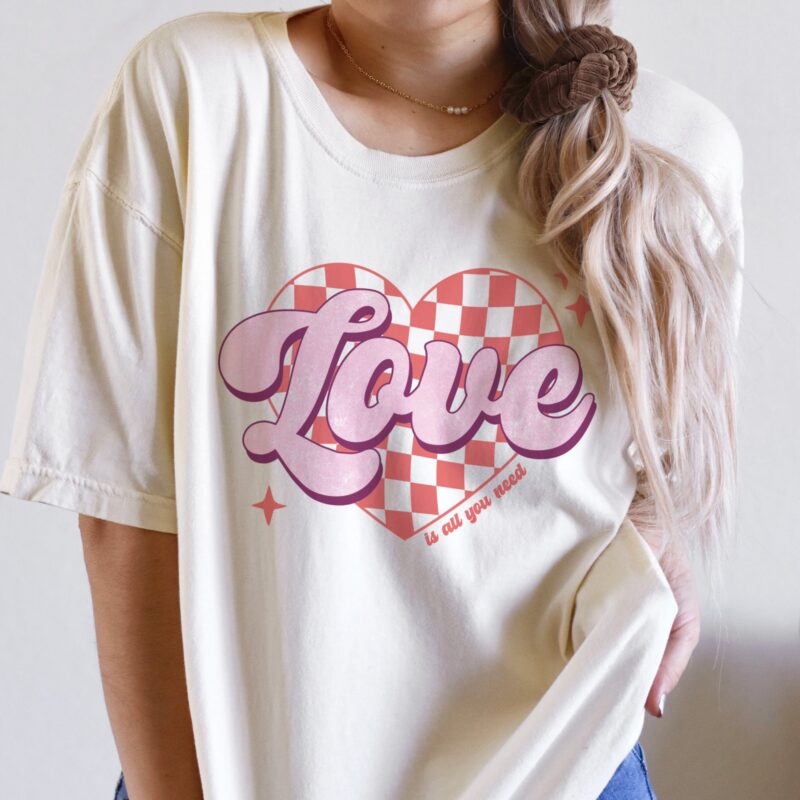 a young woman wearing a retro, love is all you need tee in Ivory