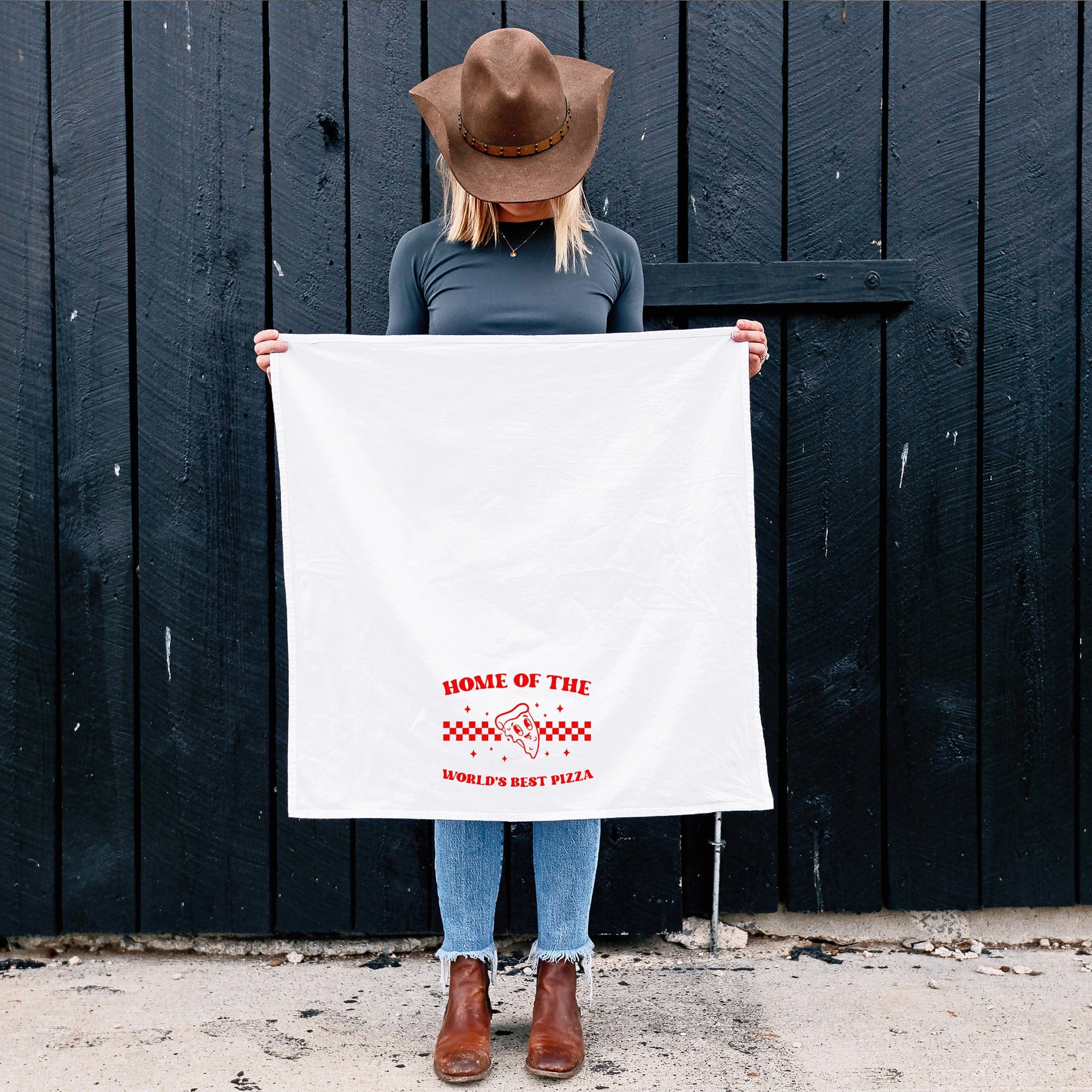 a woman holding an unfolded, home of the world's best pizza, customizable kitchen towel